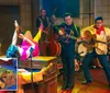 The image shows a lively scene with performers dressed in 1950s attire playing guitars and a double bass on stage while a person wearing vibrant clothing is upside down with legs in the air in front and theres a superimposed picture of a plate of food featuring what appears to be meat vegetables and bread