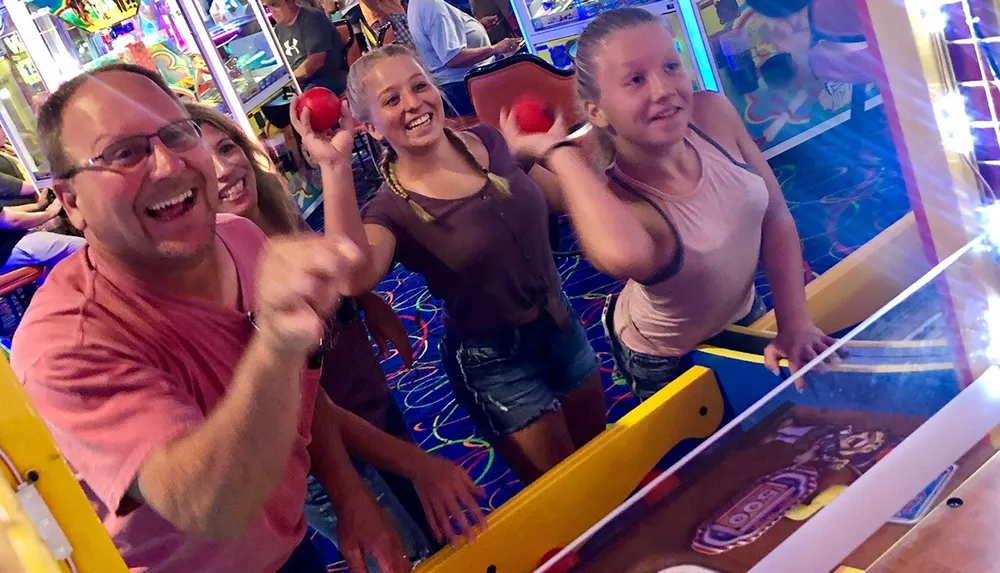 A family is happily playing a game of skee-ball in an arcade