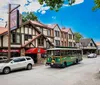 A quaint street scene featuring Tudor-style architecture with a trolley tour bus and vehicles parked alongside the buildings under a clear blue sky