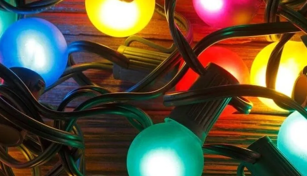 A strand of colorful illuminated spherical bulbs lies tangled on a wooden surface