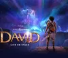 The image is a promotional poster for a stage production titled David showcasing a character gazing up at a cosmic event forming an angelic figure in a star-filled sky