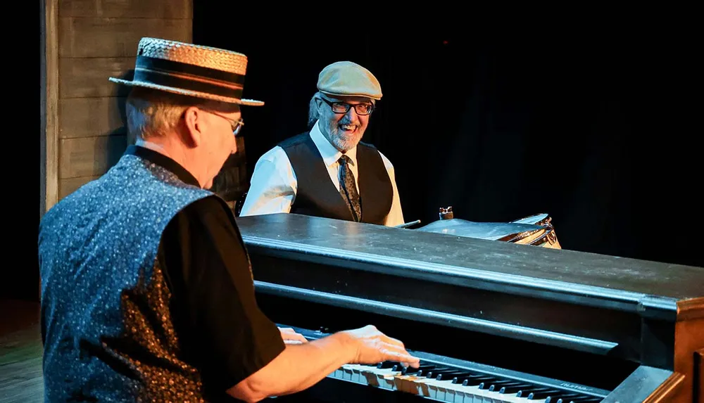 Two musicians are joyfully performing one playing a keyboard and the other smiling both wearing hats